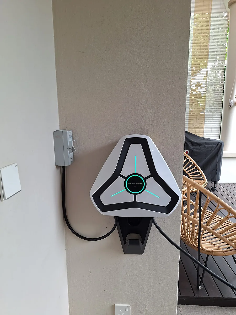 A white three-spoke wall charger with blue illuminated accents mounted on an interior wall, cable stowed on the holster below.